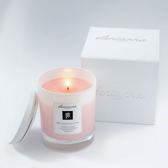 elenianna Milos Whispers of Love luxury Greek candle, shown lit in its glass vessel next to its white luxury gift box.