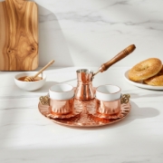 Morning coffee ritual featuring a copper Greek coffee set paired with artisanal honey and traditional pastries on a marble surface